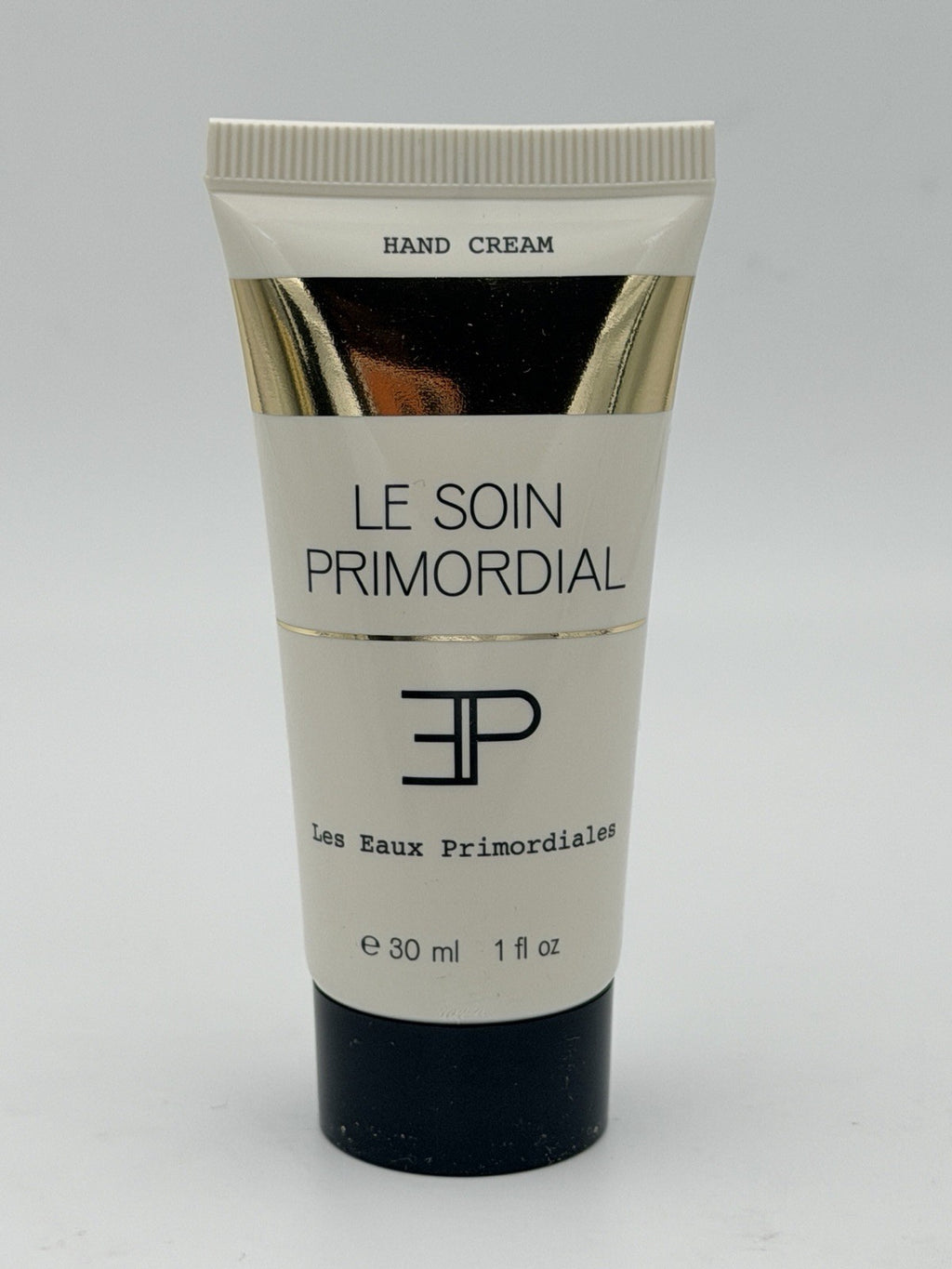 Hand cream tube labeled 'Le Soin Primordial' on a gray background